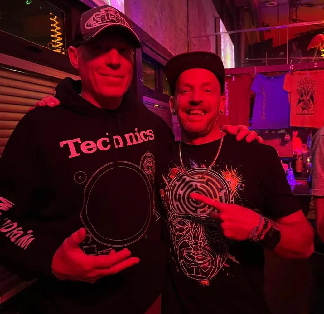 DJ Natural Nate® in Technics hoodie with a friend under red venue lighting